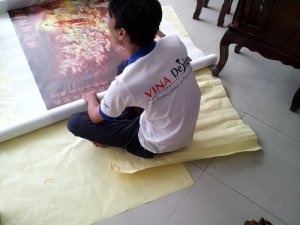 Nhân viên kiểm tra bề mặt tranh in và cuộn thành cuộn lớn, bọc cẩn thận trước khi giao hàng cho khách hàng | In tranh nghệ thuật, in tranh tôn giáo từ chất liệu silk tại In Kỹ Thuật Số