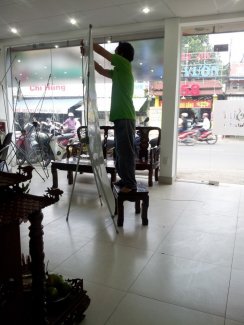 Nhân viên In Kỹ Thuật Số hướng dẫn khách hàng treo poster lên standee sao cho thẳng, đẹp, không gãy góc, không bung