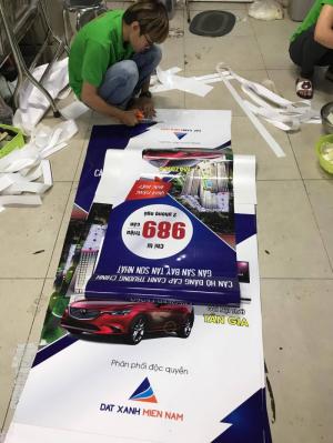 Gia công lắp 2 đầu poster vào banner cuốn - thực hiện bởi nhân viên gia công In Kỹ Thuật Số