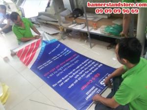 Nhân viên gia công thực hiện lắp poster vào banner cuốn cho khách hàng - khi sử dụng, chỉ cần thao tác kéo dựng lên