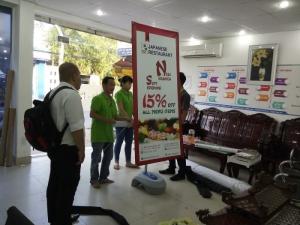Nhân viên In Kỹ Thuật Số đang lắp mẫu poster lên standee đế nước 2 mặt cho khách hàng