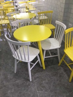 Bàn tròn gỗ màu vàng và ghế nhựa đủ màu